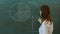 Young female teacher near chalkboard in school classroom explain something to the class