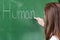 Young female teacher teaching in biology class. Teacher writing Human Body on blackboard.