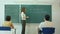 Young female teacher writing on chalkboard in class