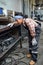 Young female technician in workwear bending in front of workbench with tools