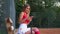 Young female tennis player is chatting on smartphone on tennis court