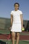 Young female tennis player standing on court with racket and ball portrait