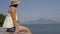 Young female tourist admires the beautiful view of the sea and mountains. Summer in Italy.