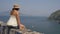 Young female tourist admires the beautiful view of the sea and mountains. Summer in Italy.