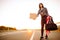 Young female tourist with american flag and bag hitchhiking along a highway. Girl holding empty cardboard. 4th July, Independence