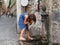Young female tourist is having break, drinking water from a city pipe