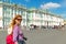 Young female tourist passes the Winter Palace in Saint Petersburg