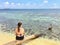 A young female tourist sitting on a log on the secluded remote tropical island of Laughing bird caye