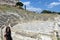 A young female tourist standing in front of the Theatre of Dionysus just below the Acropolis in Athens, Greece.