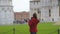 Young female tourist taking photos of the famous Leaning Tower of Pisa, Italy