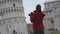 Young female tourist taking photos of the famous Leaning Tower of Pisa, Italy