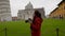 Young female tourist taking photos of the famous Leaning Tower of Pisa, Italy