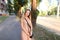 Young female tourist wearing dress standing outside with camera.