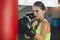 Young female trains in the gym and do boxing exercises in boxing gloves in front of a punching bag