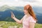 Young female traveler talking on the phone in the mountains. Portrait of positive girl use smart phone over nature