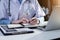 Young female in uniform of doctor using digital technology laptop for Output Device and writing a patient report on the office.