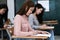 Young female university students concentrate on doing examination in classroom. Girl students seriousely writes the exercise of