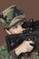 Young female US Marine Corps soldier aiming M4 assault rifle over brown background