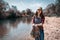 A young female volunteer ties a bag of garbage standing by the river. The concept of Earth Day and ecology and environmental