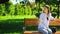 Young female waiting in park sitting on bench, appointment punctuality, time