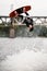 young female wakeboarder holds rope and doing flips and jumping over the water on wakeboard