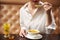 Young female in white eating tasty cream soup.