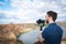 Young filmmaker filming natural landscape in canyon with a large river and marshes