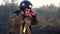 Young fireguard in uniform putting helmet on countryside at the scene of emergency. Professional male firefighter