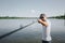 Young fisherman fishing on lake or river. Concentrated serious guy holding long rod with hands and looking forward