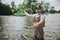 Young fisherman fishing on lake or river. Picture of serious concentrated guy in fishing rob stands in water and using