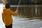 Young fisherman. preschooler boy in yellow jacket is fishing on river bank. View from back. Male hobby. Leisure outdoors. nature,