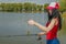 Young fisherwoman preparing for fishing. Girl with fishing rod looks at lure