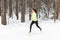 Young fit athlete woman running at forest Sprinting during winter training outside in cold snow weather.