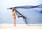 Young, fit and beautiful woman on the beach dancing with silk