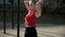 Young fit busty woman in red top collecting hair in ponytail at sports ground