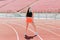 Young fit female in sportswear and protective mask for coronavirus on track during outdoor workout