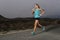 Young fit sport woman running outdoors on asphalt road in mountain fitness workout