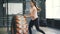 Young fit sportswoman lifting heavy rubber tyre during crossfit workout indoors