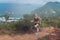 Young fit tanned woman trail running up the steps carved into the hillside with mountains, sea, islands and cloudy sky