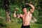 Young fit topless bodybuilder outdoors demonstrating muscles
