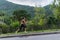 Young fit woman doing cardio exercise, listening to music, running outdoors with green mountain landscape in the