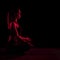 Young fit woman meditating. Neon red light. Modern sci fi representation of yoga. Copy space.