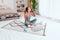 Young fit woman in sportswear drinks water while doing everyday morning warm up exercises on the floor at home