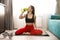 Young fit woman in sportwear drinks water while doing everyday morning warm up exercises on the floor at home, sportive lifestyle