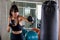 young fitness girl doing exercise hitting punching bag at a boxing studio gym.woman boxer in sportswear working out with gloves.