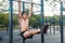 Young fitness man doing hanging leg raises exercise working out his abs in the park.