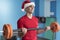 Young fitness Santa Claus training in gym lifting weights with b