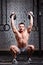 Young fitness sportsman exercising cross fit with kettlebell against brick wall in the gym.