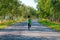 Young fitness white woman running up to turn country road, rear view