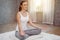 Young fitness woman in casual wear practicing yoga with mat on floor in bedroom at home in Morning . sport girl doing meditating
